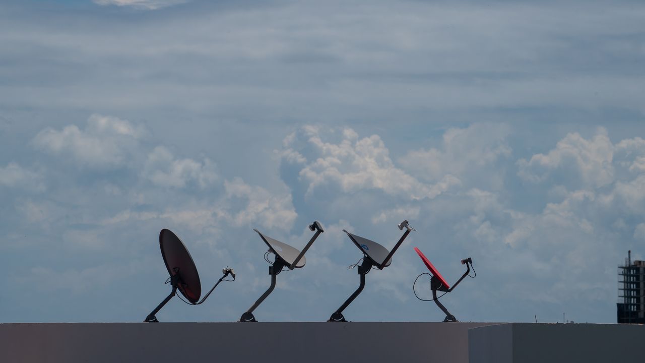 why-choose-us Four satellite dishes on a rooftop against a cloudy sky in Cancún, Mexico.